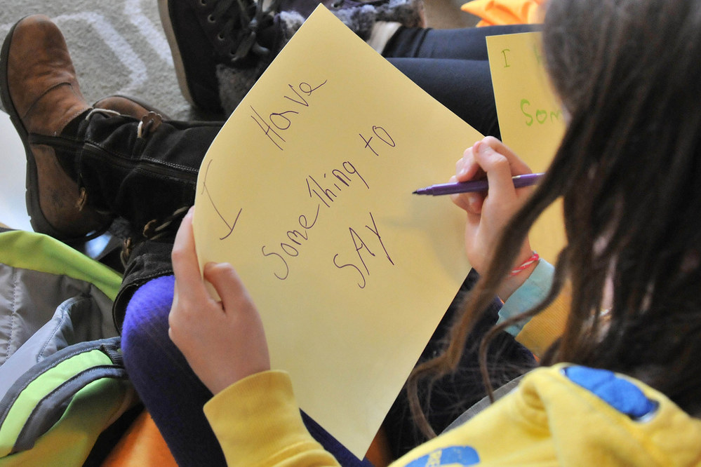 The cardboard reads "I have something to say" at a young girls workshop exploring what being a girl means and getting tips on how to start a campaign in their bedroom. Led by Caroline Bird. Photo by: Southbank Centre.