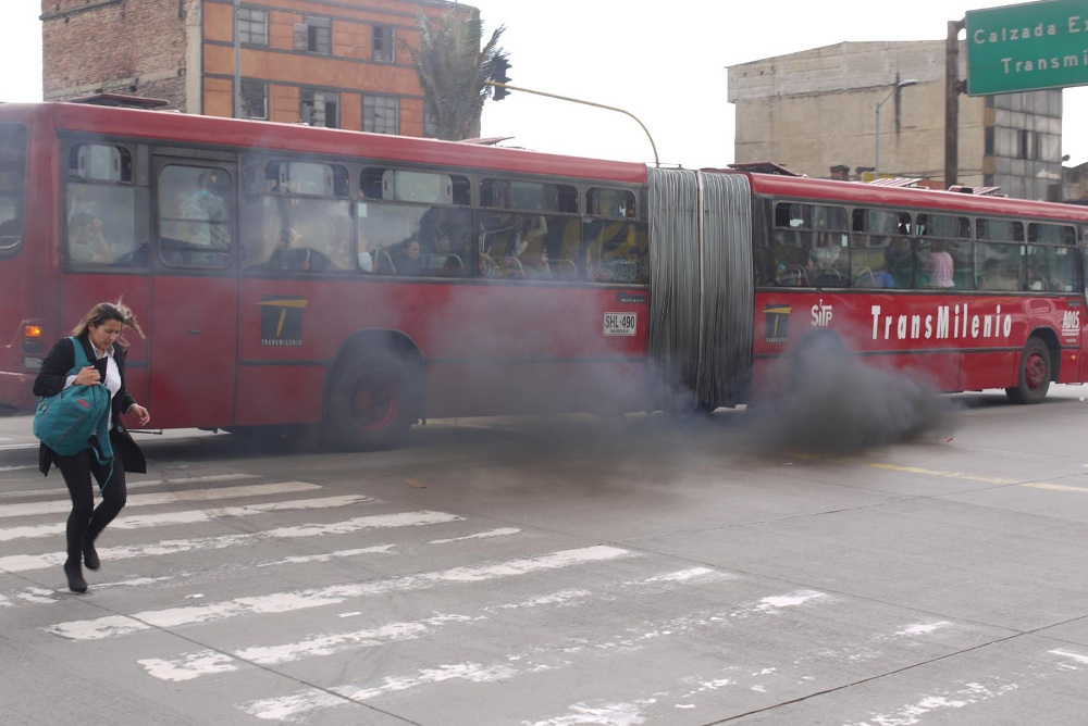 Woman escaping the smoke caused by the iconic TransMilenio bus in Bogotá, Colombia. Photo by: Mike Ceaser.